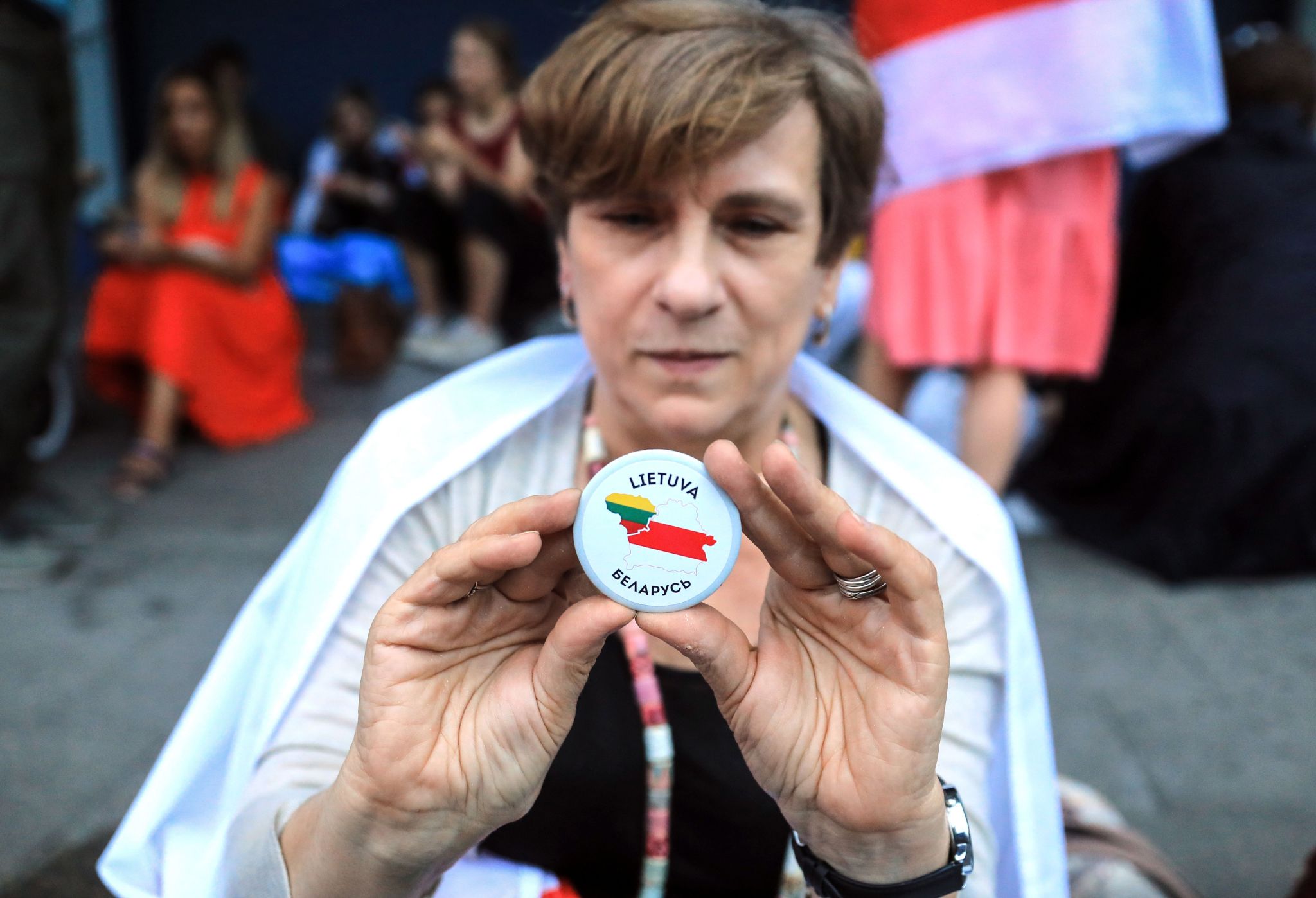A woman stands with a button with Lithuania and Belarus country shapes on it during a protest